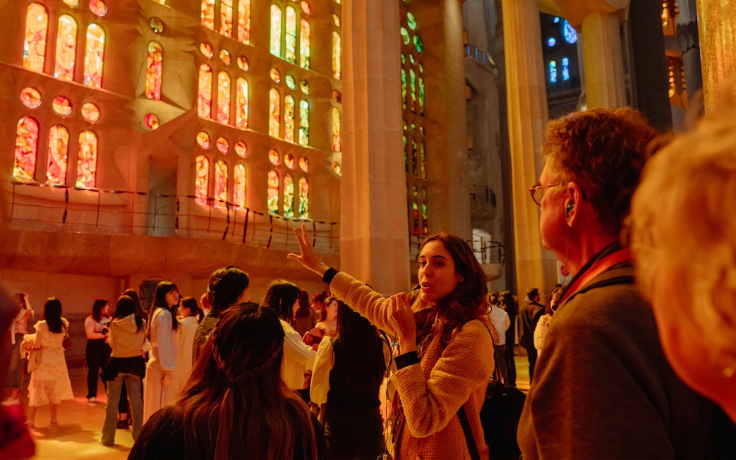 Tour guide explaining Sagrada Familia's stained glass interior to visitors.