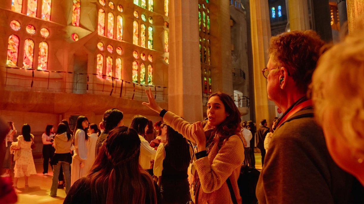 Tour guide explaining Sagrada Familia's stained glass interior to visitors.