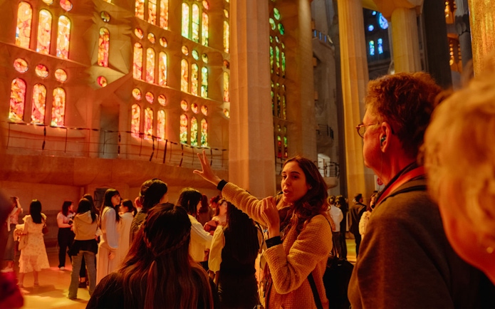 Tour guide explaining Sagrada Familia's stained glass interior to visitors.