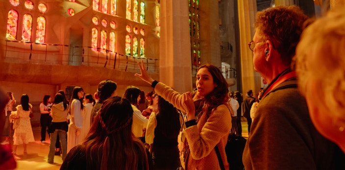 Tour guide explaining Sagrada Familia's stained glass interior to visitors.
