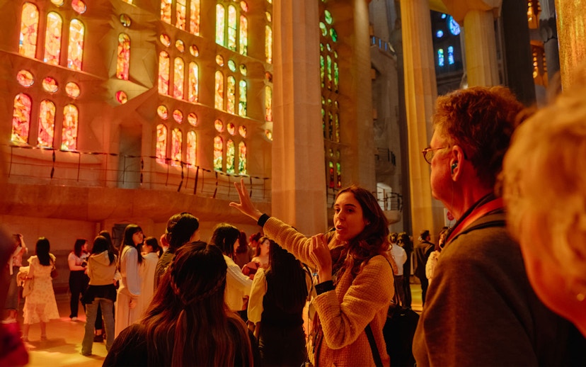 Tour guide explaining Sagrada Familia's stained glass interior to visitors.