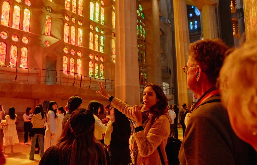 Tour guide explaining Sagrada Familia's stained glass interior to visitors.