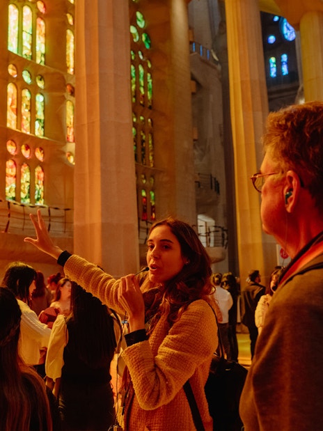 Tour guide explaining Sagrada Familia's stained glass interior to visitors.