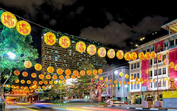 Chinatown night scene with dragon lanterns and illuminated buildings.