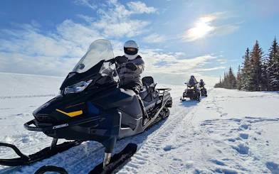 Snowmobiles on a snowy trail in Fairbanks, Alaska, with riders exploring the winter landscape.