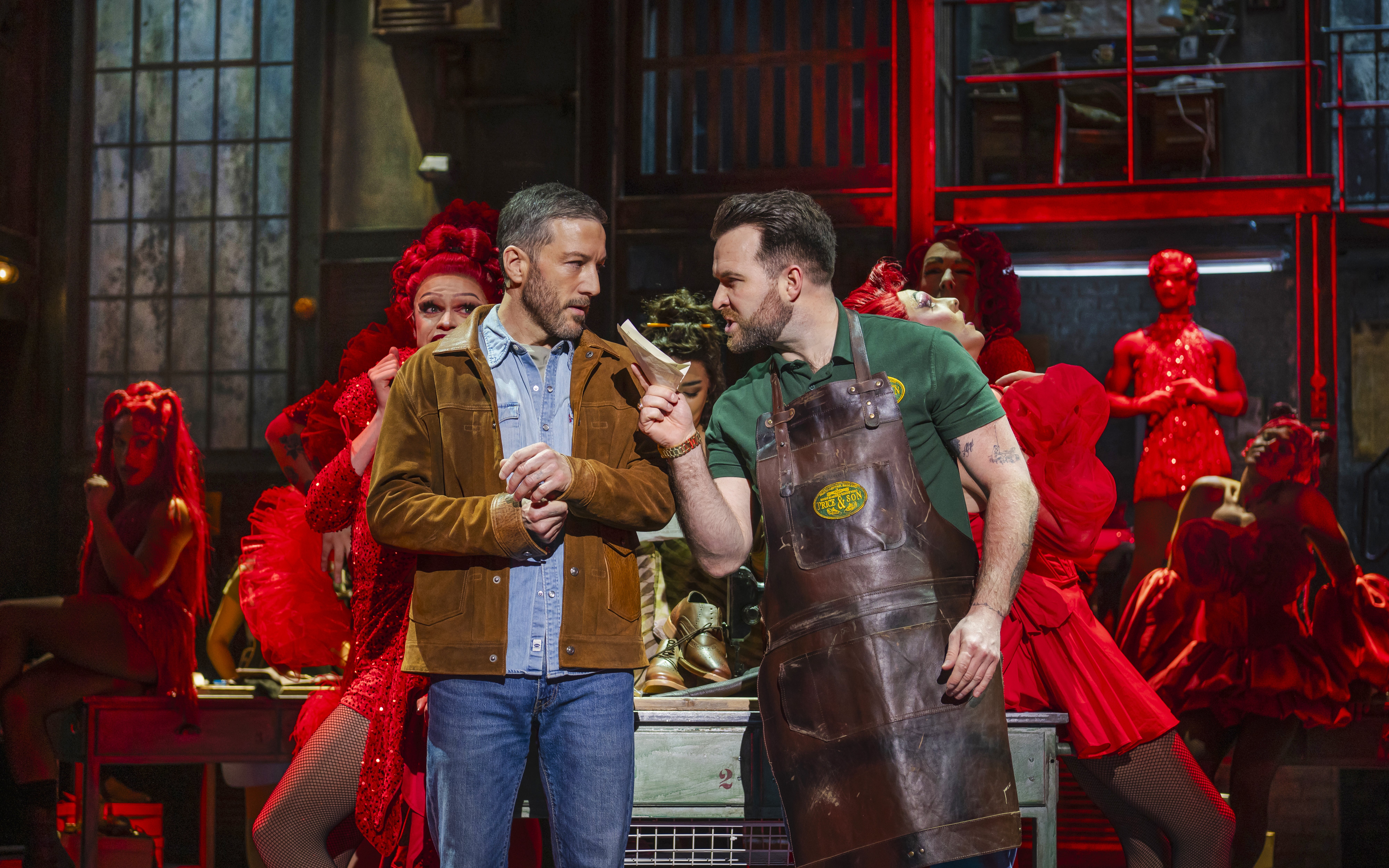 Actors performing a scene from Kinky Boots with vibrant costumes and dramatic expressions.