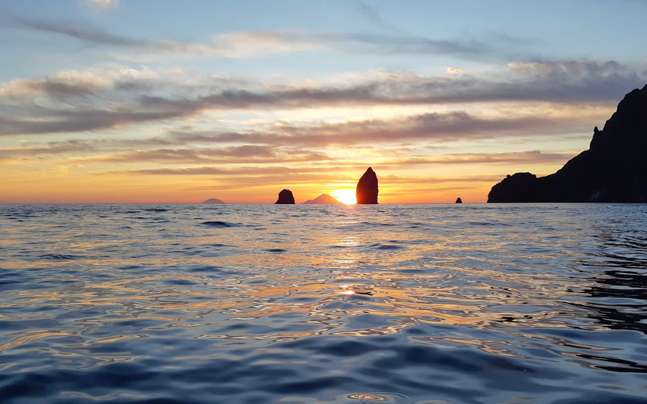 Sunset view from a boat tour between Lipari and Salina, highlighting sea stacks.