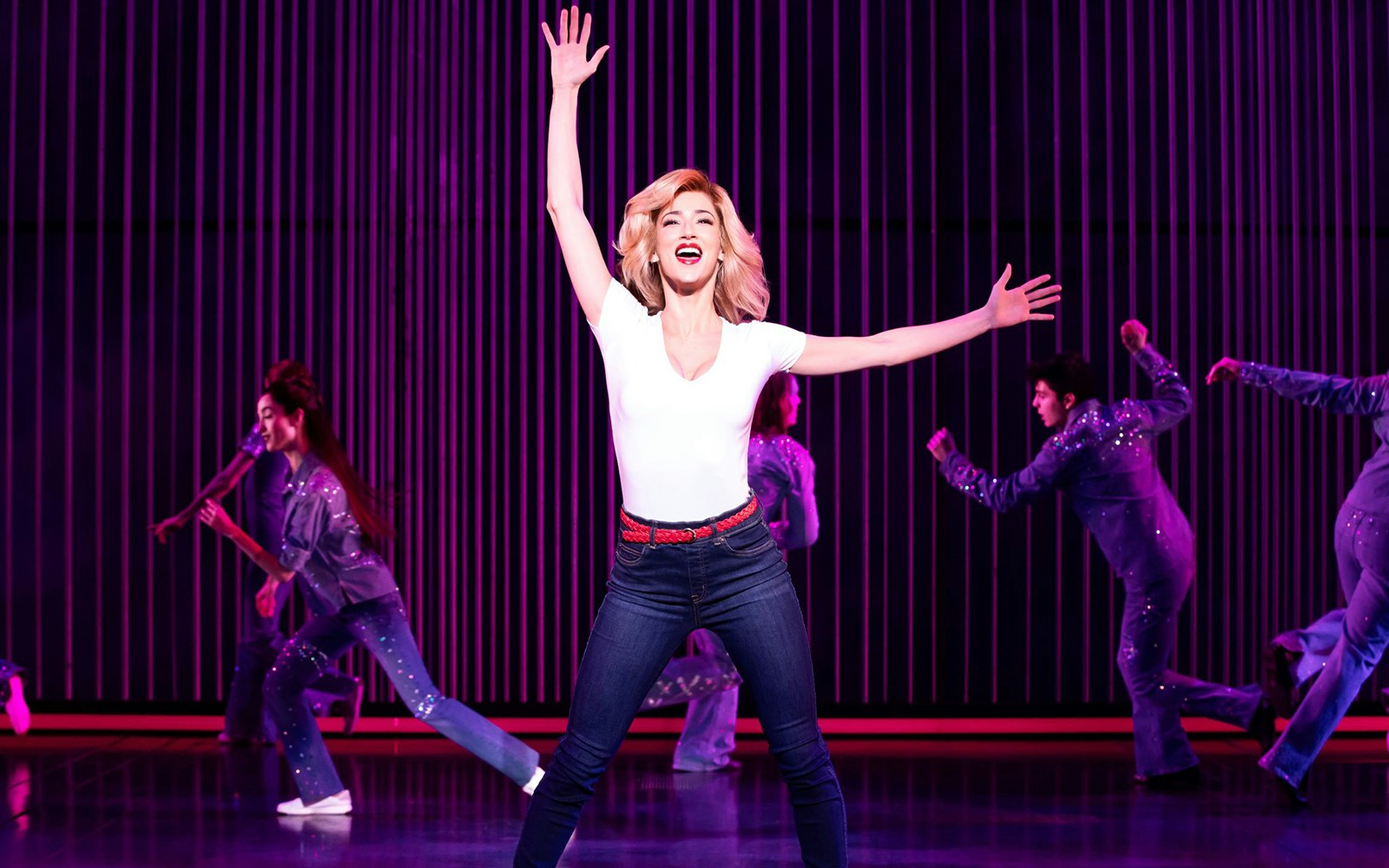 Performer on stage during "A Beautiful Noise: The Neil Diamond Musical" with dancers in background.