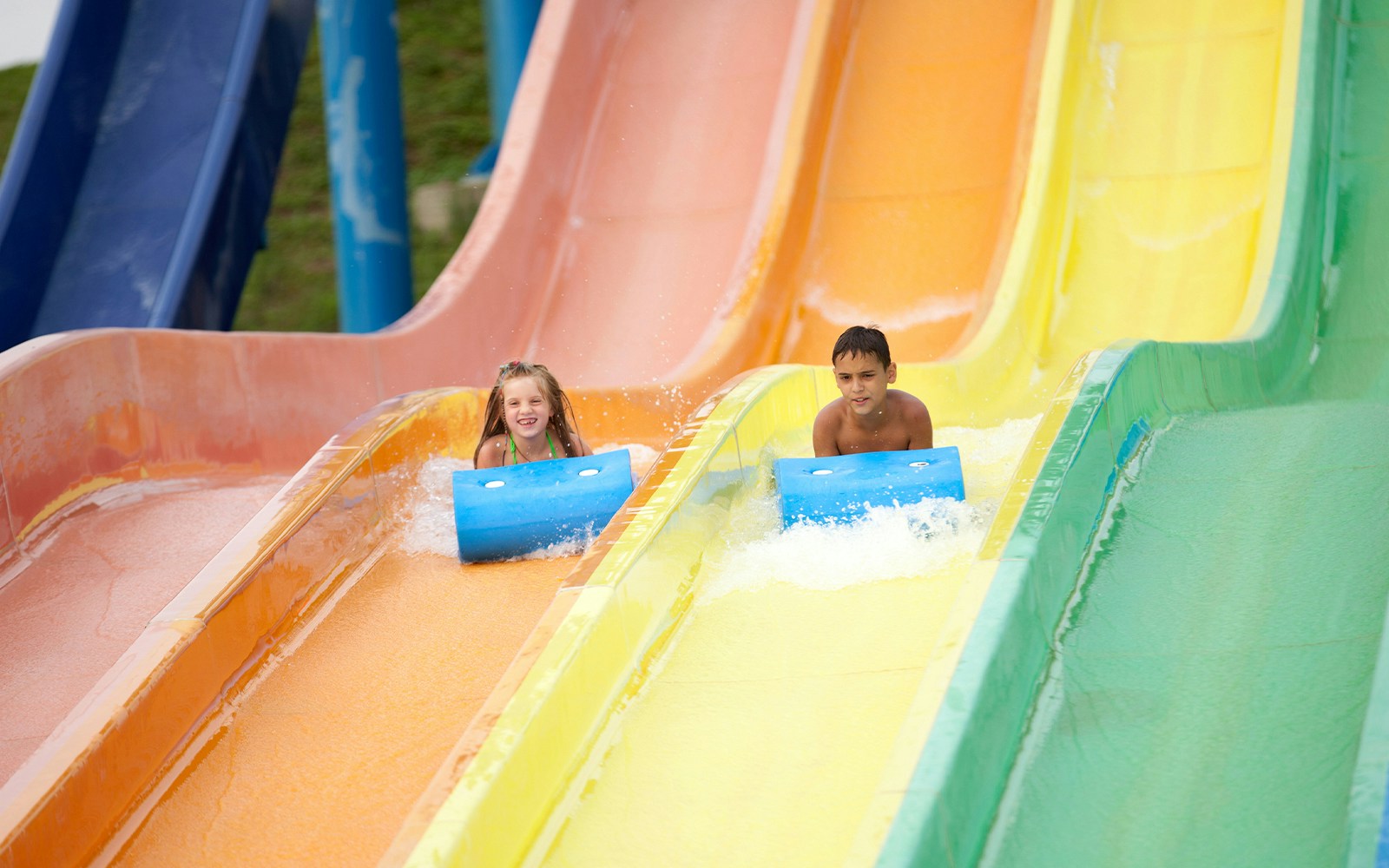 Children sliding down colorful water slides at a summer water park.
