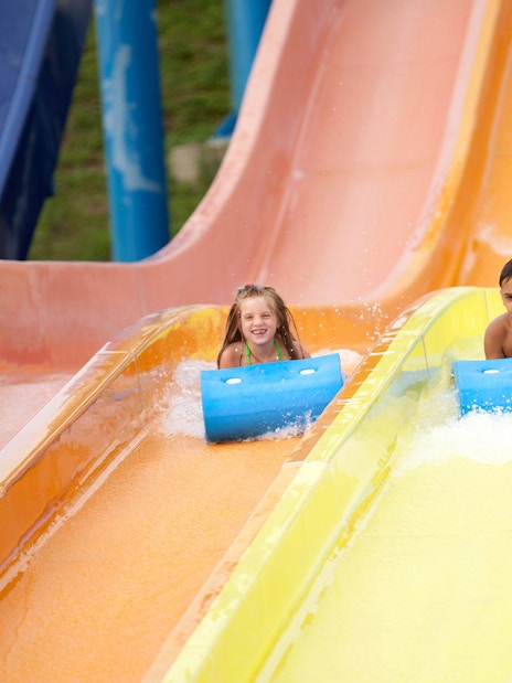 Children sliding down colorful water slides at a summer water park.