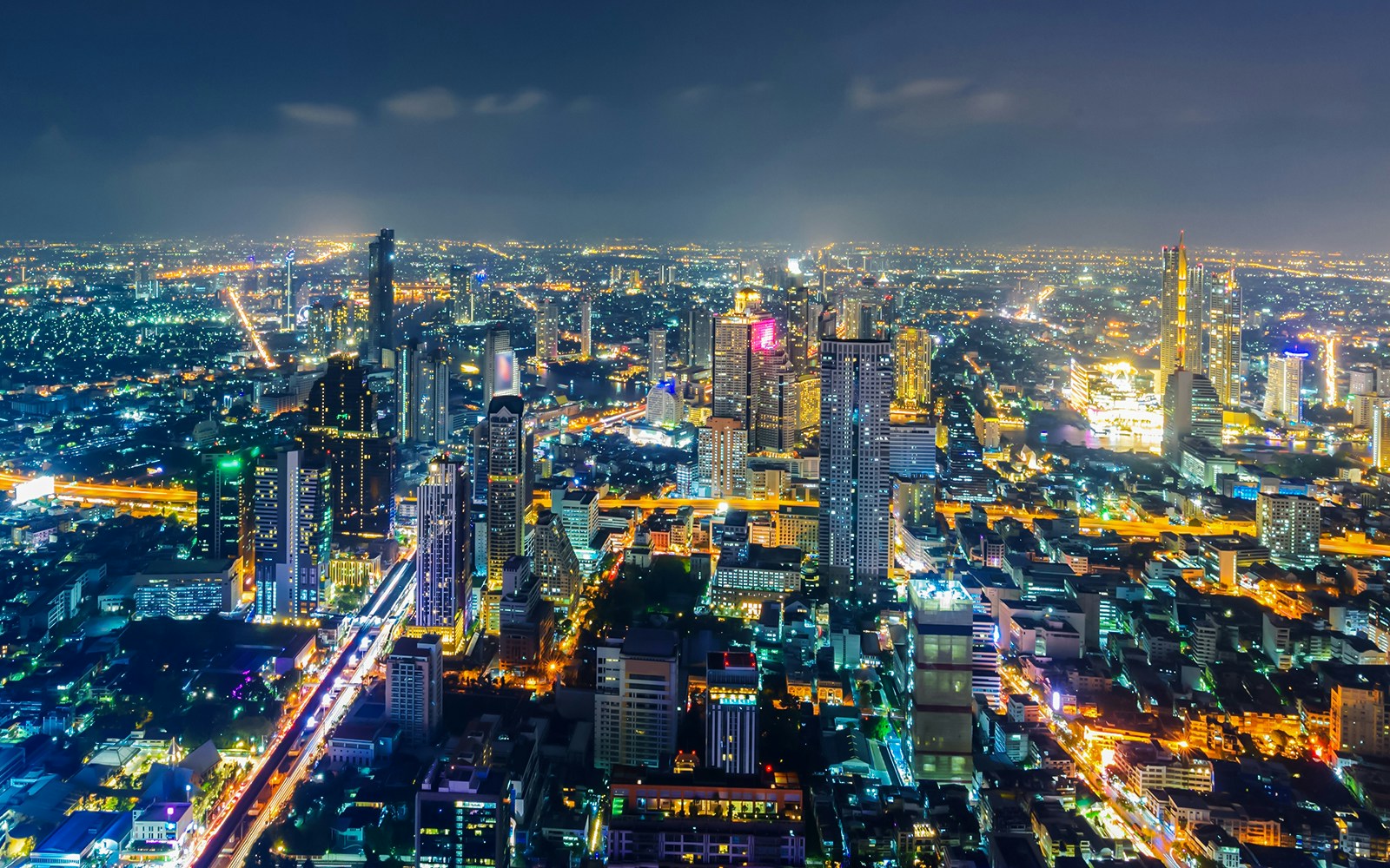 Bangkok skyline illuminated at night with skyscrapers and city lights.