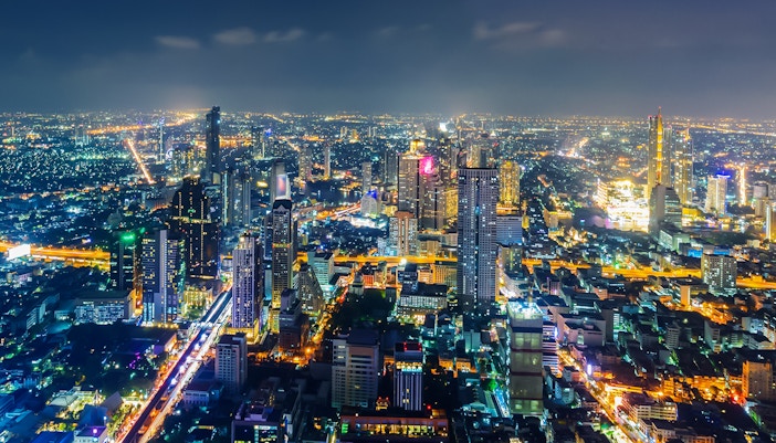 Bangkok skyline illuminated at night with skyscrapers and city lights.