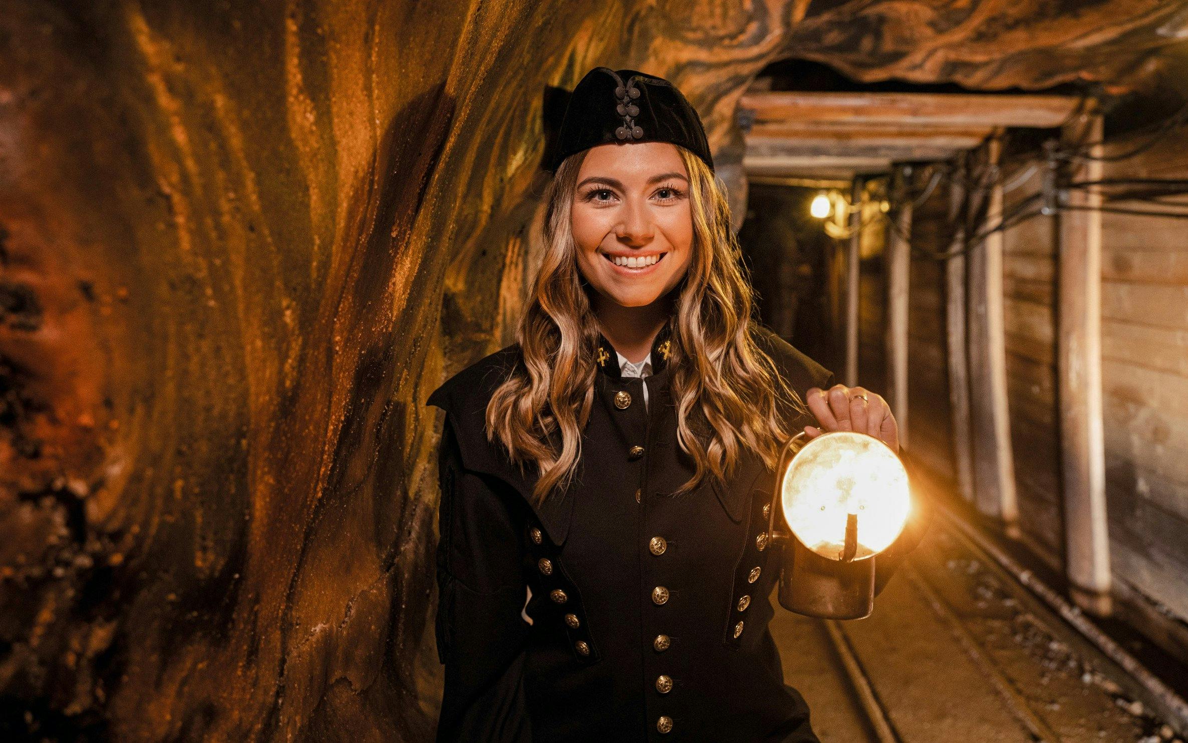 Tour guide in traditional miner attire holding a lantern inside Hallein salt mines, Salzburg.