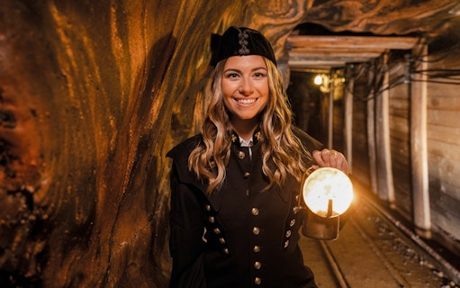 Tour guide in traditional miner attire holding a lantern inside Hallein salt mines, Salzburg.