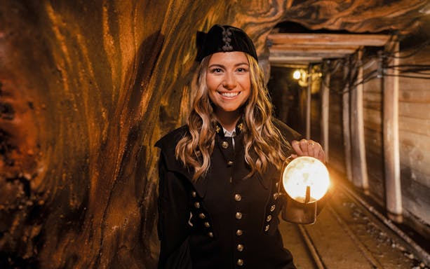 Tour guide in traditional miner attire holding a lantern inside Hallein salt mines, Salzburg.