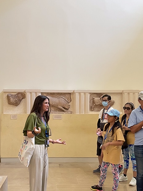 Tour guide explaining ancient statues to visitors inside Delphi Museum.