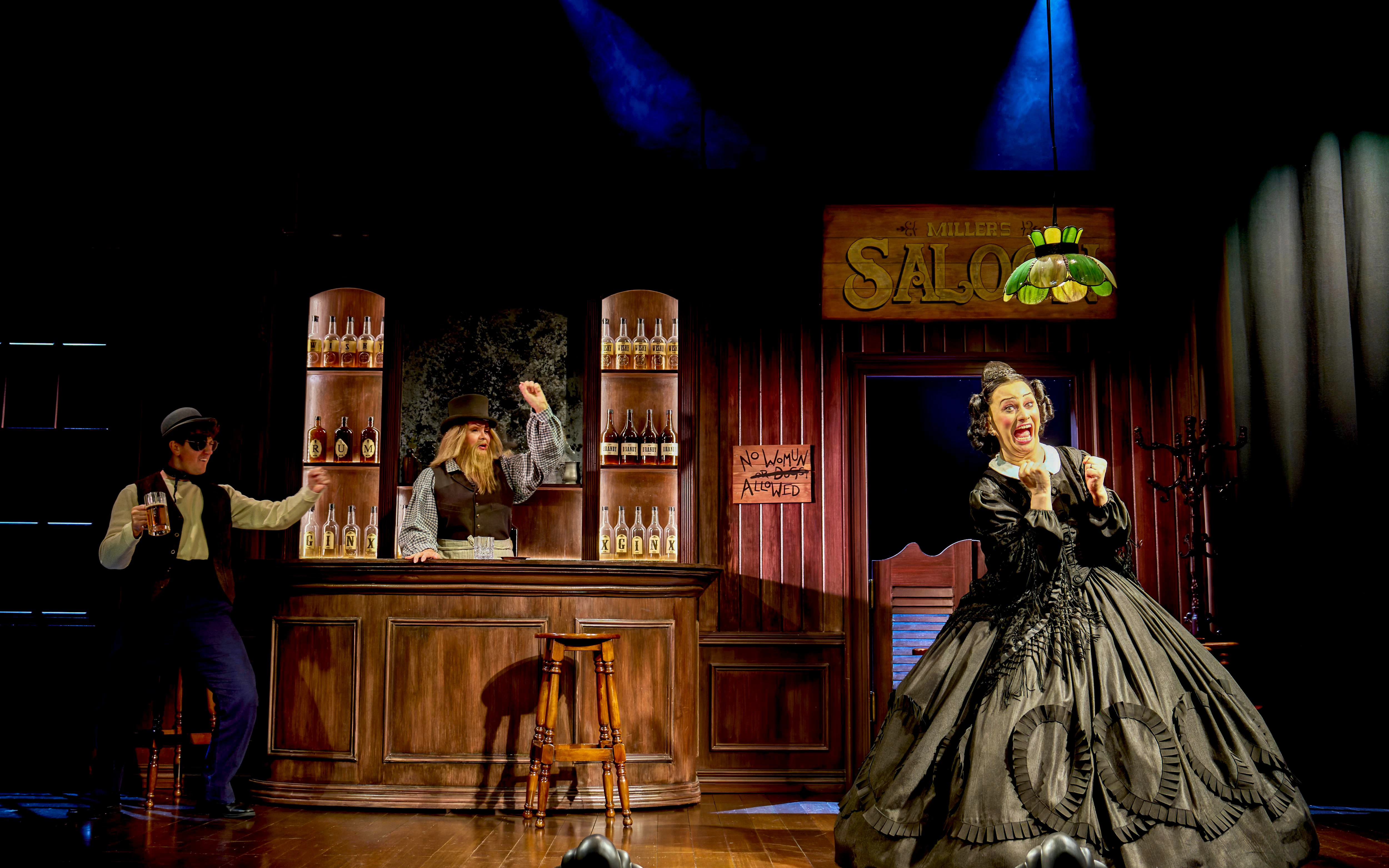 Saloon scene from "Oh Mary!" with actors in period costumes, one behind the bar, another holding a mug.