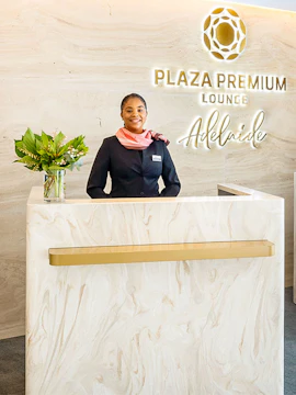 Reception desk at Plaza Premium Lounge Adelaide with staff member.