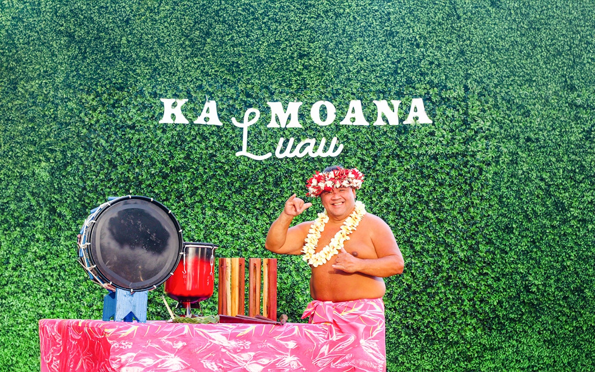 Performer at Ka Moana Luau in Hawaii with traditional drums and floral lei.