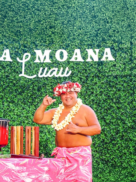 Performer at Ka Moana Luau in Hawaii with traditional drums and floral lei.