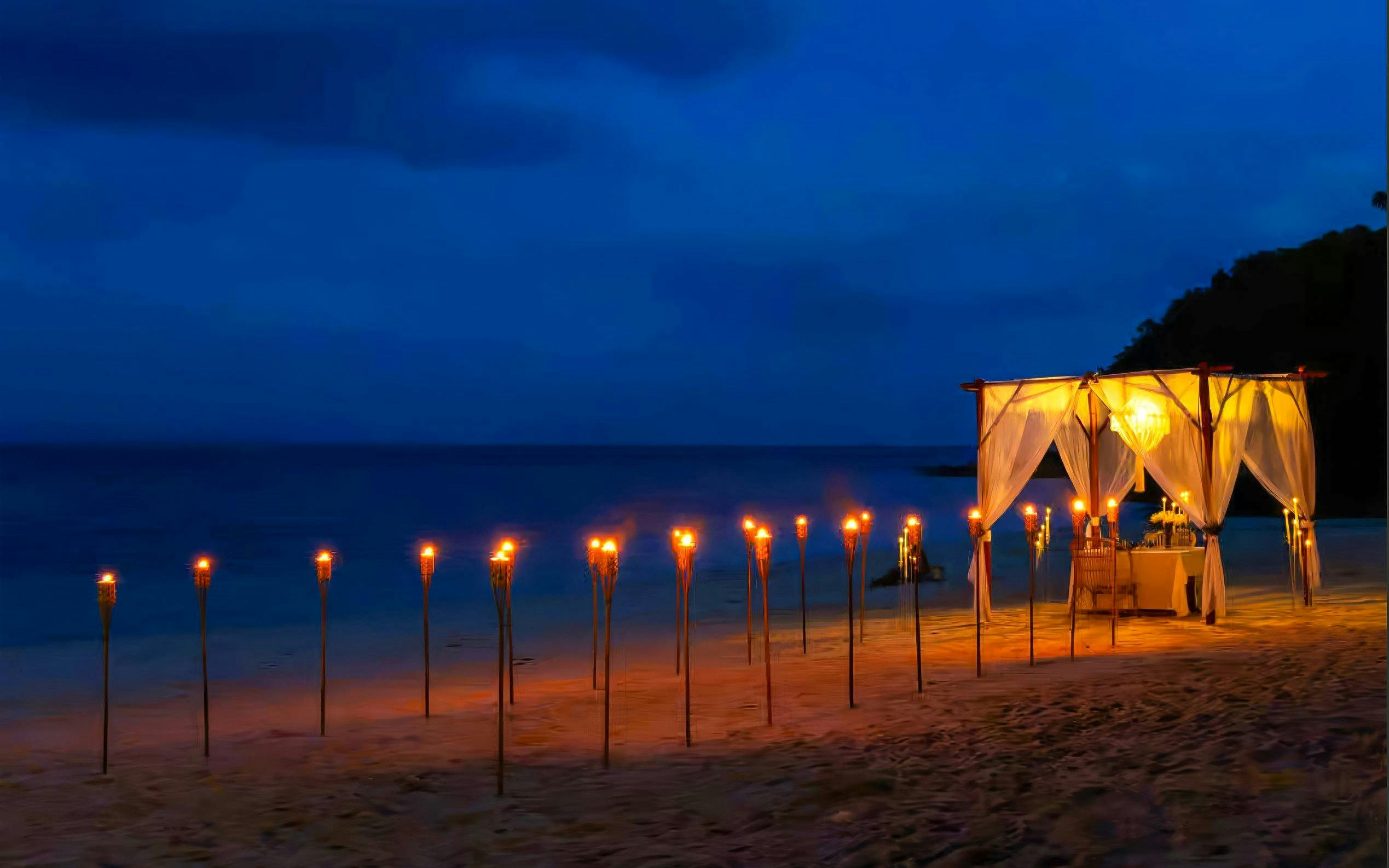 Private cabana with torches on Banana Beach Koh Hey at night.