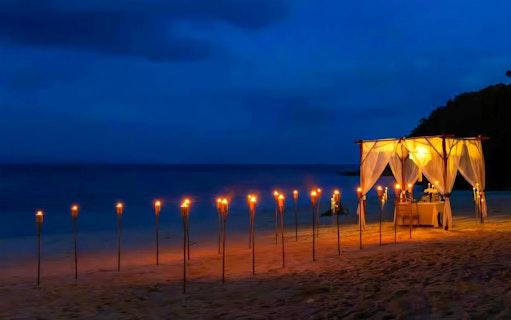 Private cabana with torches on Banana Beach Koh Hey at night.