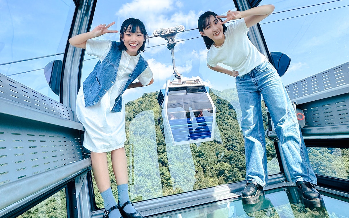 Tourists posing inside cable car on Lantau Island with scenic view.