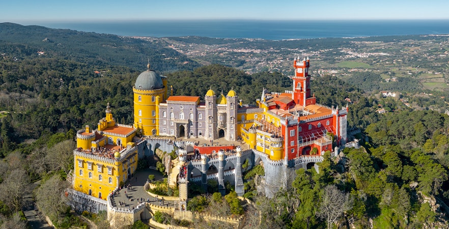 Pena Palace in Sintra with colorful turrets and lush forest surroundings.