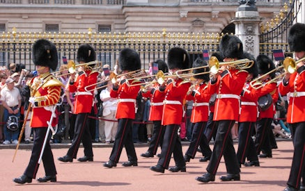 Guards in red uniforms and bearskin hats perform at Changing of the Guard, London.