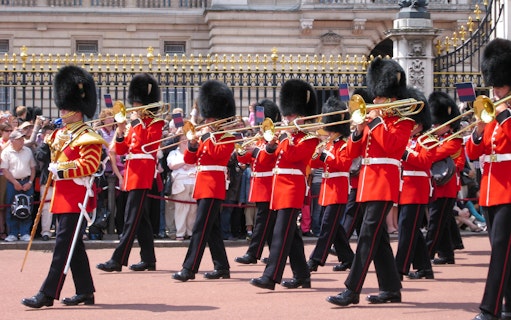 Guards in red uniforms and bearskin hats perform at Changing of the Guard, London.