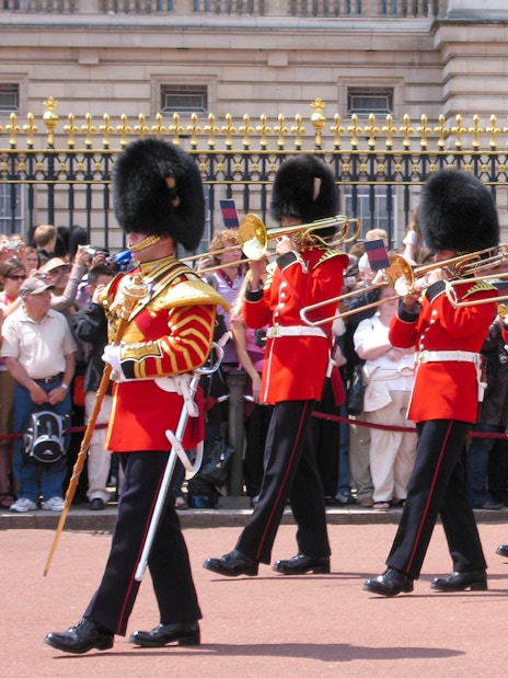 Guards in red uniforms and bearskin hats perform at Changing of the Guard, London.