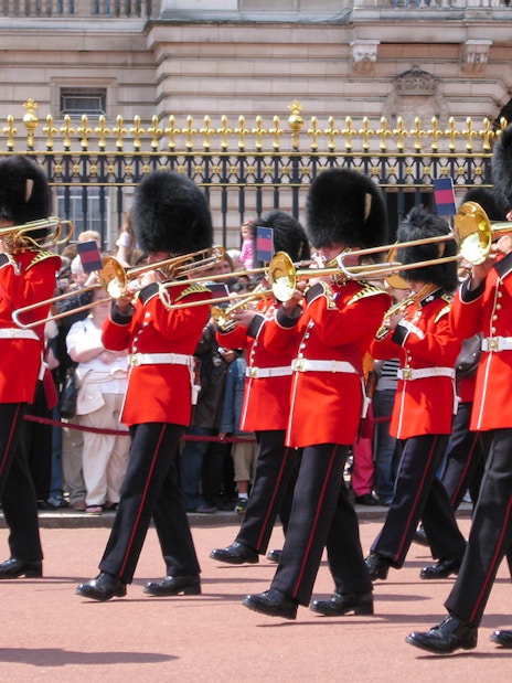 Guards in red uniforms and bearskin hats perform at Changing of the Guard, London.