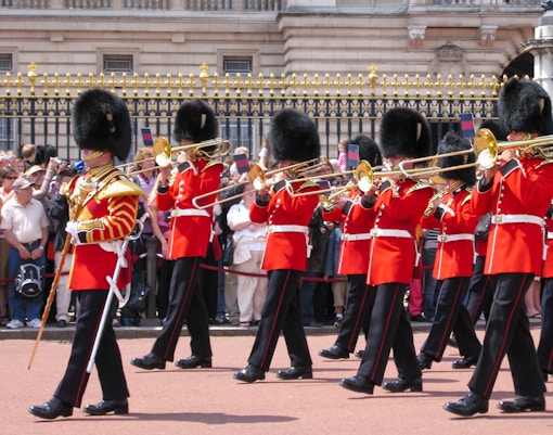 Guards in red uniforms and bearskin hats perform at Changing of the Guard, London.