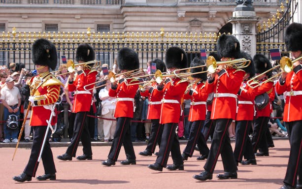 Guards in red uniforms and bearskin hats perform at Changing of the Guard, London.