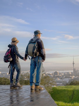 Couple watching sunrise over Auckland from Mt Eden summit.