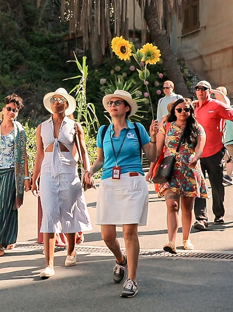 Tour group exploring Cinque Terre village street on a sunny day.