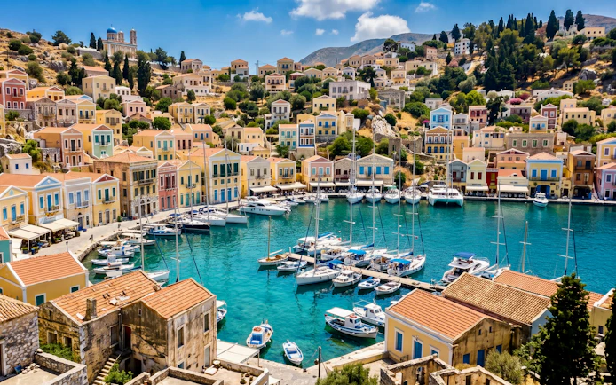 Colorful houses and boats in the harbor of Symi Island, Greece.