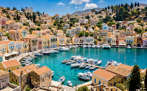 Colorful houses and boats in the harbor of Symi Island, Greece.