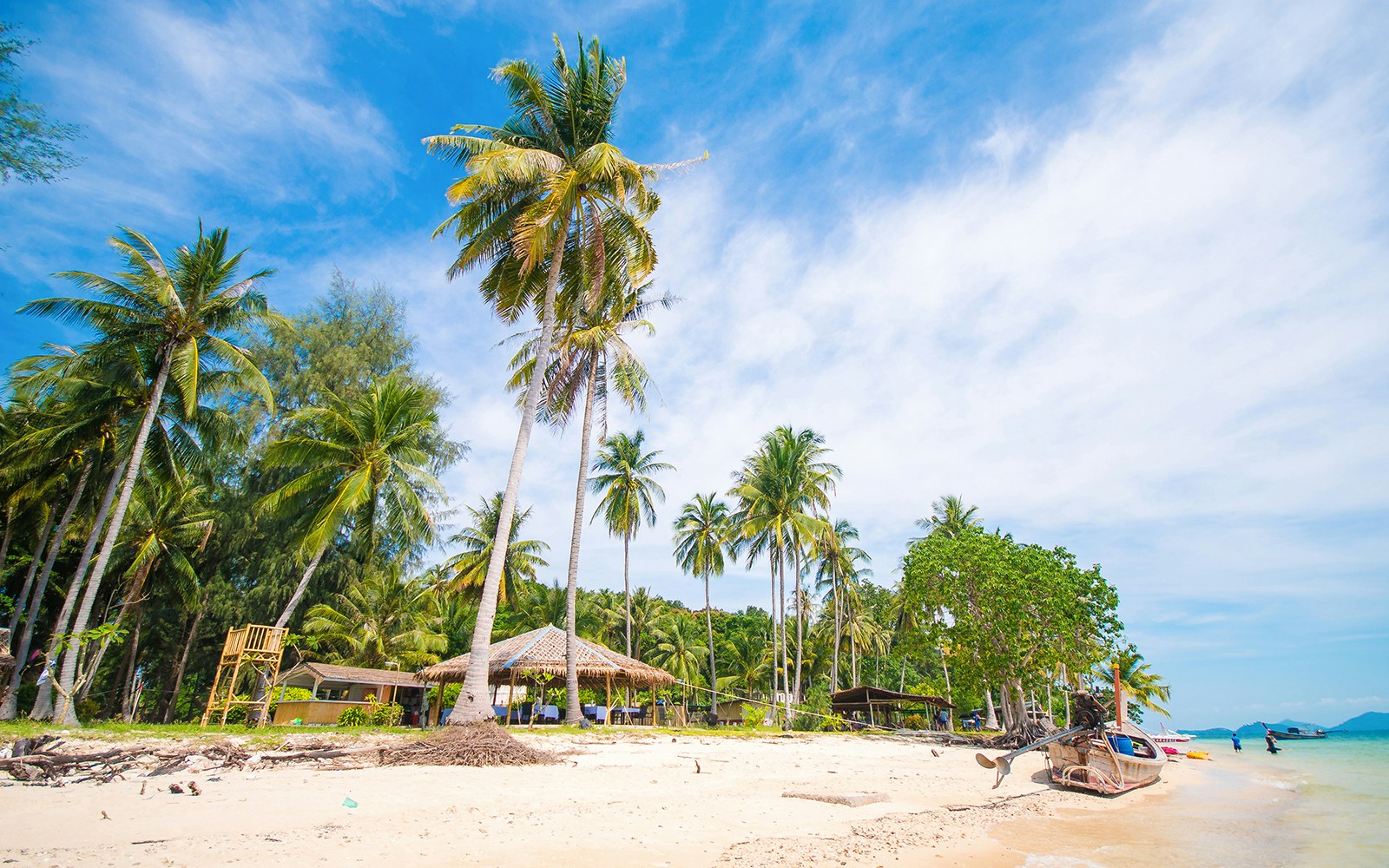 Naka Noi Island beach with palm trees and boats, Phuket, Thailand.