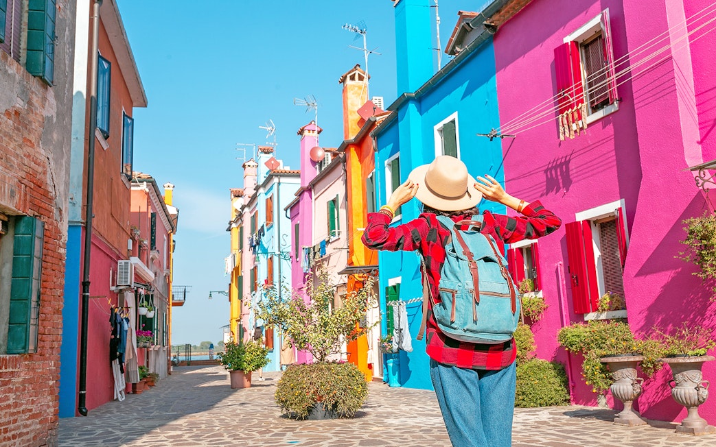 Woman exploring colorful buildings on Burano Island, Italy.