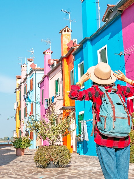Woman exploring colorful buildings on Burano Island, Italy.