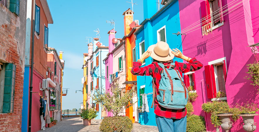 Woman exploring colorful buildings on Burano Island, Italy.