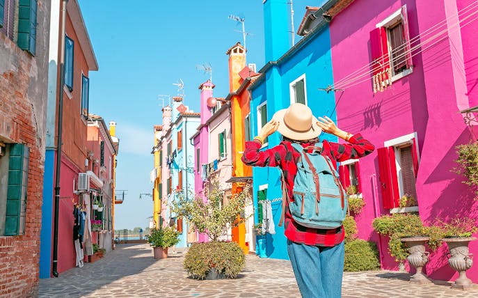 Woman exploring colorful buildings on Burano Island, Italy.