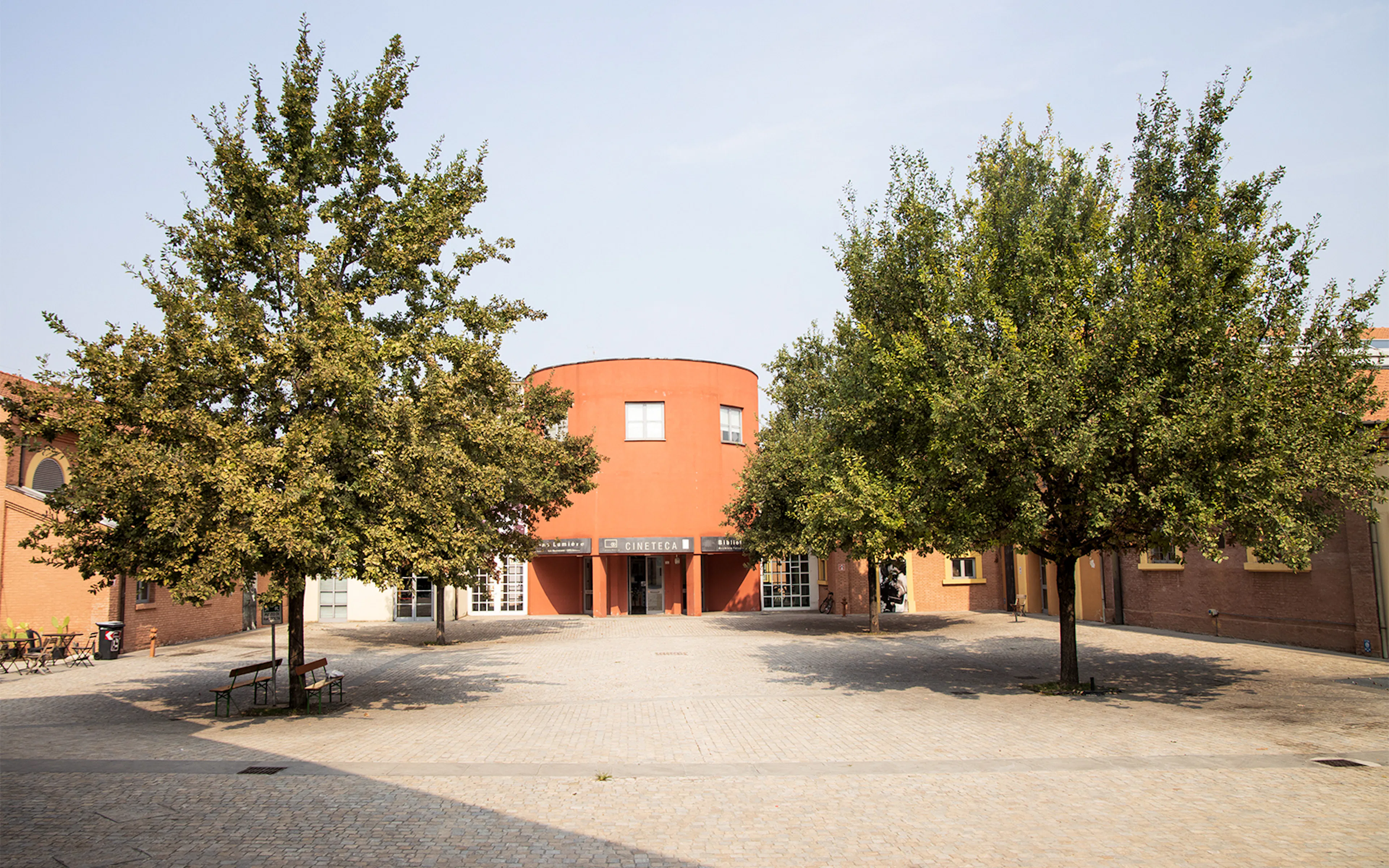 Courtyard with trees and red building in Ostia Antica, Italy.
