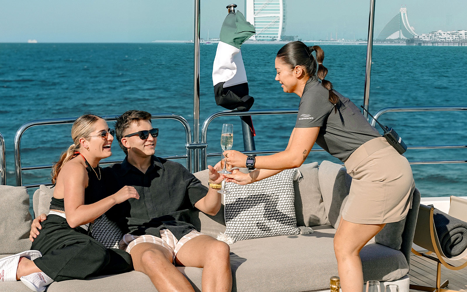 Couple enjoying drinks on a Sunseeker superyacht with Dubai skyline in the background.