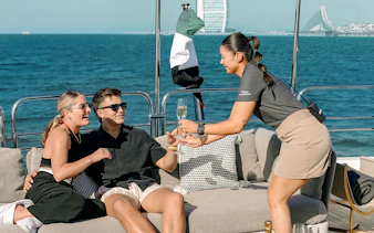 Couple enjoying drinks on a Sunseeker superyacht with Dubai skyline in the background.