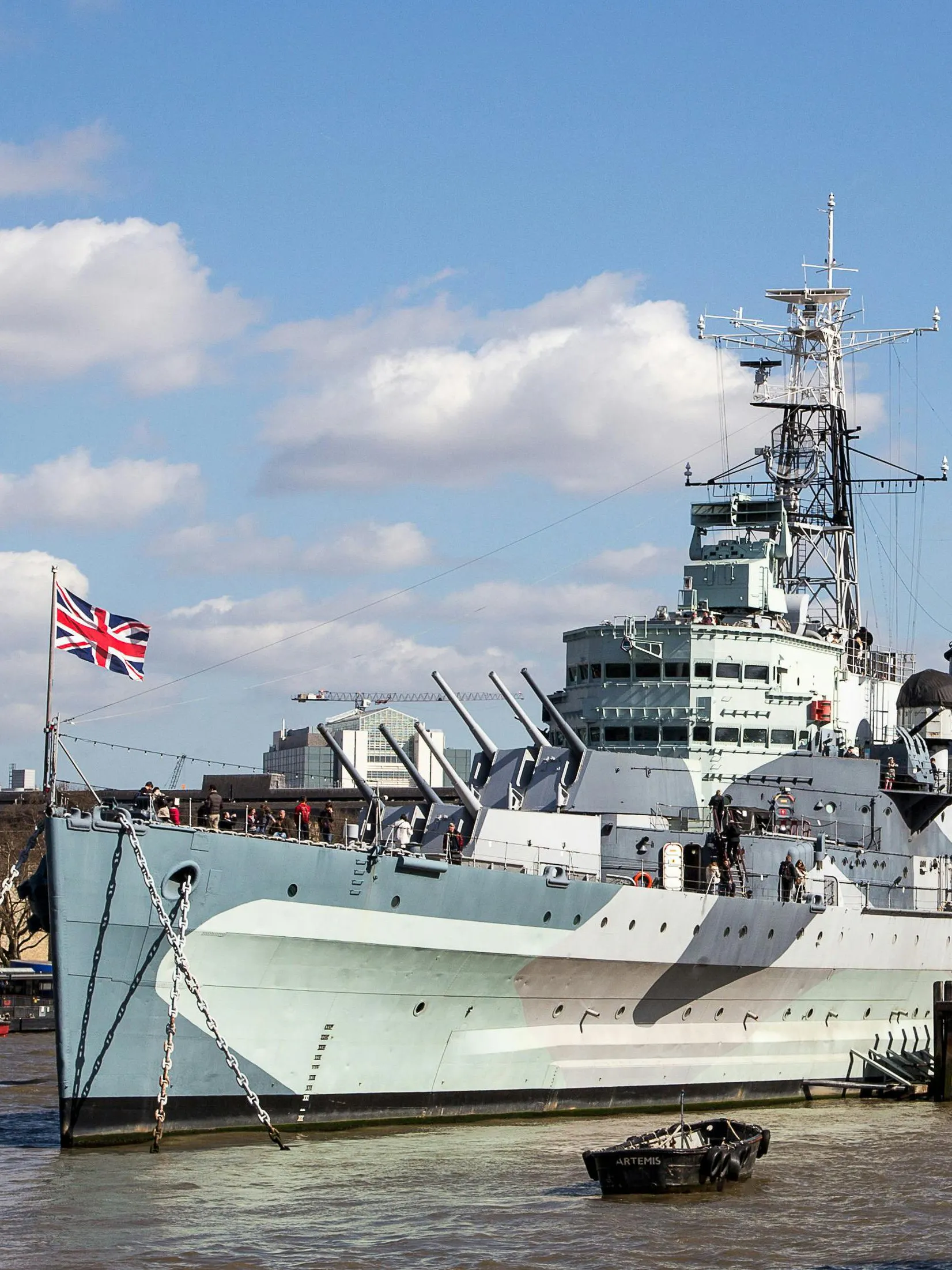 HMS Belfast moored on the River Thames in London with visitors on deck.