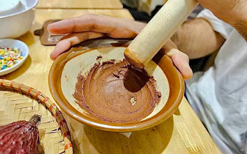Grinding cocoa beans in a bowl during a chocolate workshop in Hanoi.