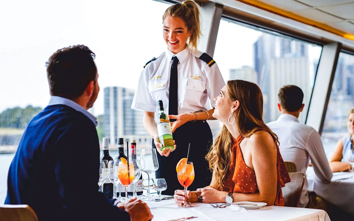 Server presenting wine to a couple on a Sydney Harbour lunch cruise.