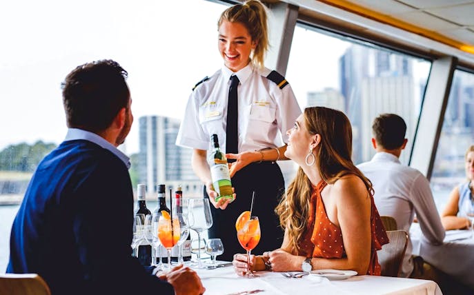 Server presenting wine to a couple on a Sydney Harbour lunch cruise.